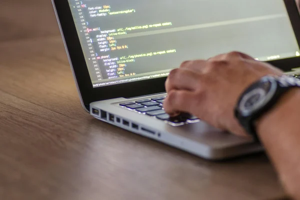 Developer using AI coding assistant on laptop with code on screen