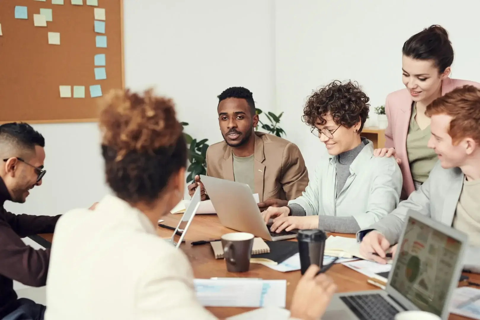 Sales development reps collaborating around a laptop in an open office