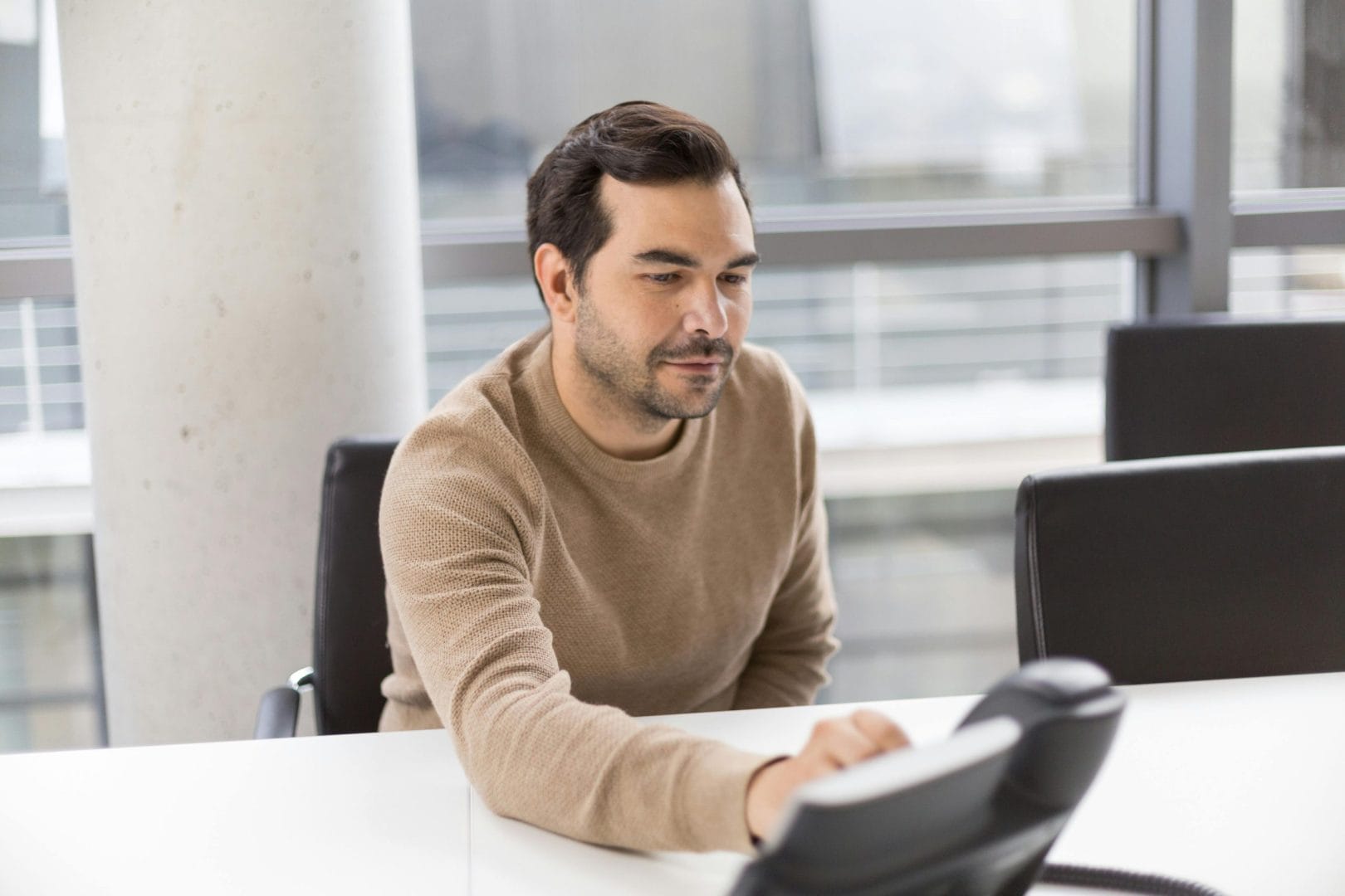 Professional using business desk phone representing virtual phone system comparison