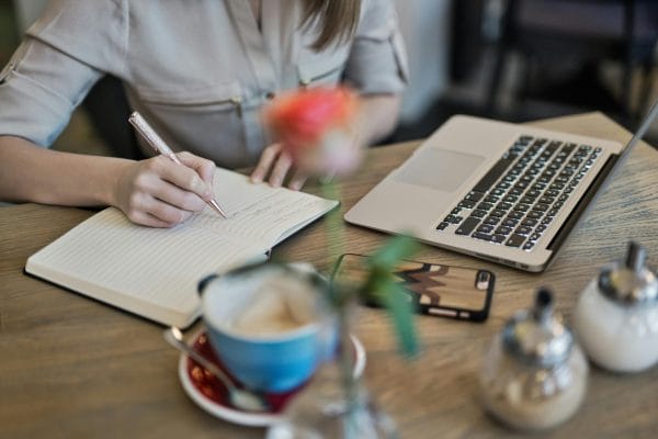 Writer with notebook and laptop representing AI copywriting tools for ecommerce