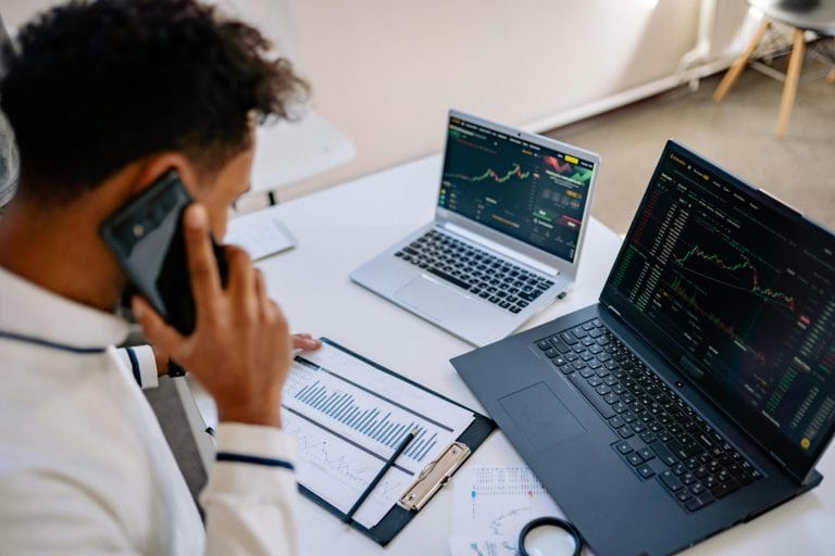 Sales rep on phone analyzing data on laptop representing AI sales calling platforms