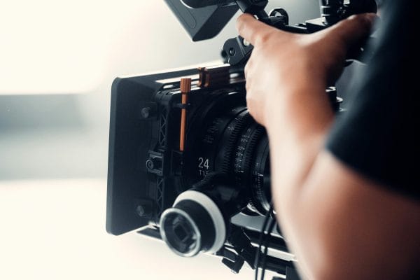 A professional video camera being operated by a person during filming indoors.