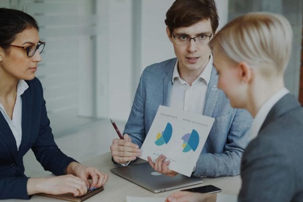 Team of professionals discussing sales strategies with charts in a modern office.