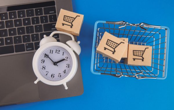 Shopping basket, boxes and alarm clock isolated on blue background. Online shopping concept.